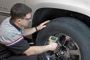 A Goodwrench technician checks the wheels and tires with a Tire Pressure Monitoring Systems (TPMS) tool.