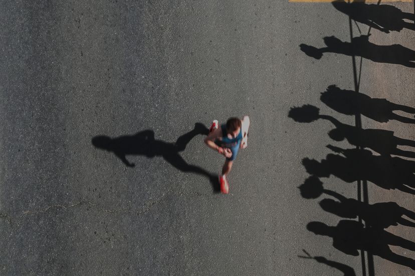 Summer Sports Background. Unknown People Running Marathon Distance And Waving For Fans Looking Event. Real Life, Top View, Ambient Light, Sun And Shadow, Copy Space, Blurred Motion