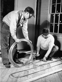 Two men actively installing a radiant floor heating system.&nbsp;