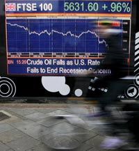 A cyclist passes a financial display screen showing the FTSE 100. See more recession pictures.