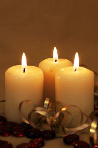 Three candles with gold ribbon and red beads , vertical