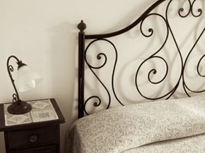 Old bed with lamp at hotel in Sicily (Italy).