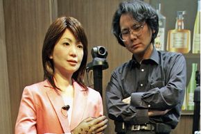 石黑浩(Hiroshi Ishiguro)在2005年日本长谷世界博览会的原型机器人展览上展示他的Repliee机器人的早期版本＂border=