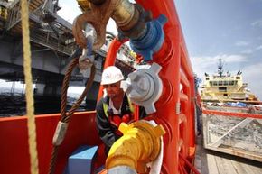 Worker turns a valve on vessel while drilling relief well