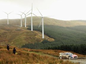 在威尔士兰格里格举行的英国威尔士拉力赛上，丹尼·索多(Dani Sordo)开车经过一个风力发电场。＂border=