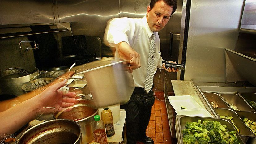 Health inspector Richard Lavin passes a container of prepared food to be disposed for violating health standards during an inspection at the China Bowl fast food restaurant in Los Angeles. Ricardo Dearatanha/Los Angeles Times via Getty Images