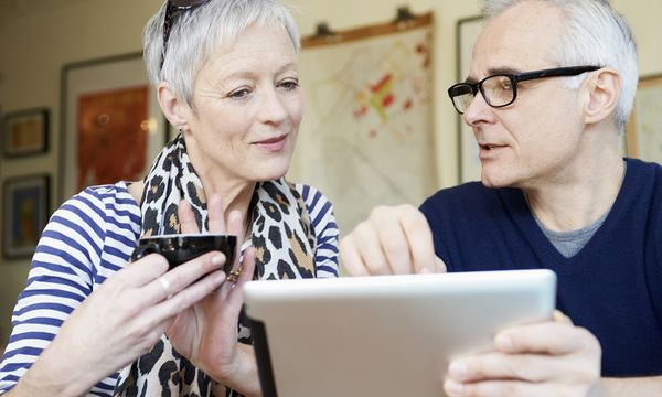 Mature man and woman in cafe with digital tablet