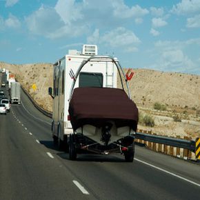  A trailer tows a small boat on the highway.