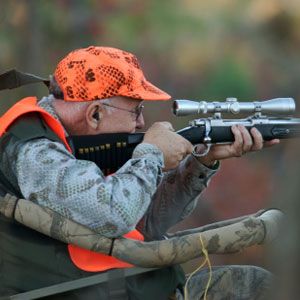 Men outdoors hunting with rifles.