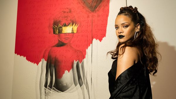 singer rihanna poses in front of album artwork