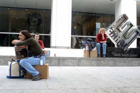 Meredith Stewart (left), who worked at Enron, sits on her personal belongings in front of the company's headquarters after being laid off in 2001.