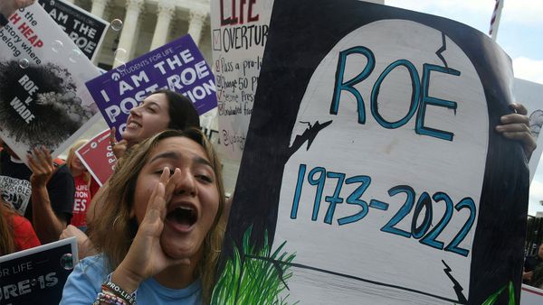 Women outdoors protesting in a sign-wielding protestor.