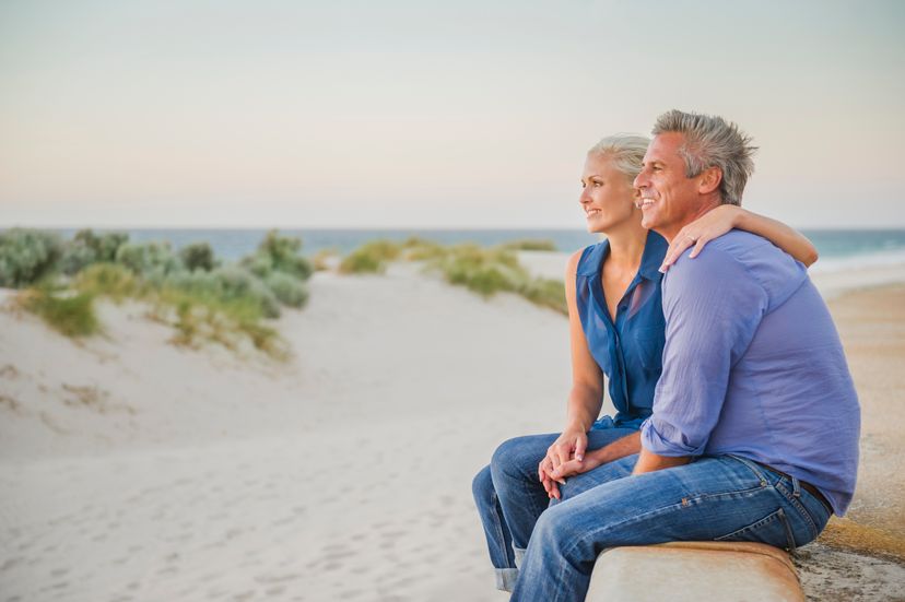 Caucasian couple hugging on wall at beach