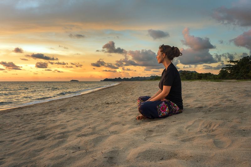 woman meditating on a sunset beach