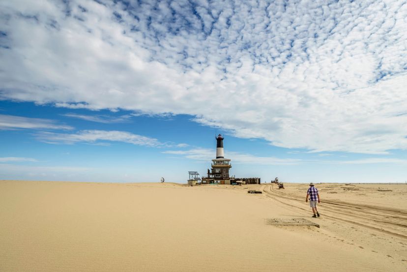 Person walking towards a lighthouse in desert
