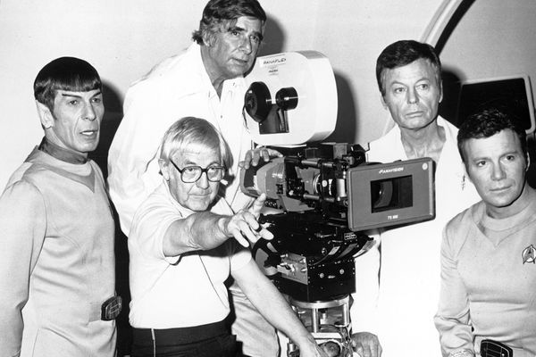 Men with equipment, tripod, looking at camera in black and white.