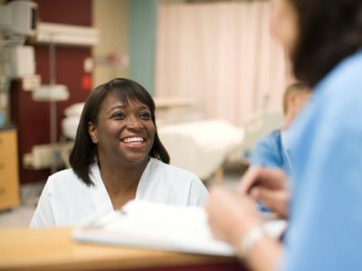 Female nurse talking to doctor at desk in hospital