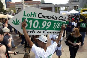 Javier Martinez uses a sign to advertise for LoHi Cannabis Club dispensary at an April 2012 rally for legalized marijuana in Colorado.  In November, voters in that state approved a measure to legalize the drug. See more controlled substance pictures.
