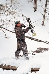 Hunter braves winter outdoors in snowy landscape.