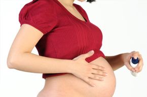 Pregnant woman applying spray to her stretchmarks