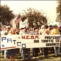 Protestors march with signs outdoors in a crowd.