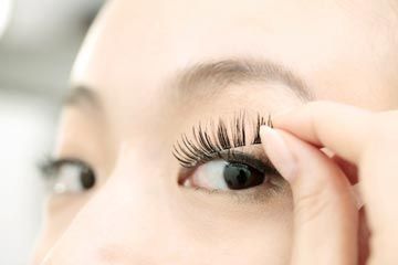 woman applying false eyelashes