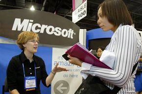密歇根州立大学的学生Mikaela Mackin(右)在威斯康辛州密尔沃基市举行的女工程师协会年会上与微软的招聘人员Jennifer Orchard交谈。, 2004年。”width=