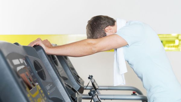 man standing over treadmill