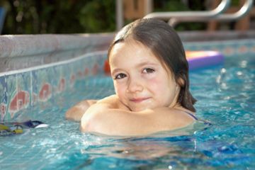 Child swimming alone in pool of water.