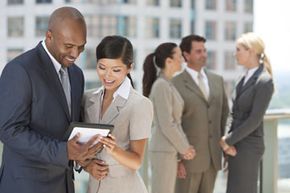 interracial group of  businessmen and women look at tablet