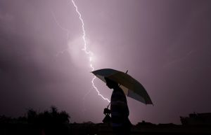 A person walks with an umbrella in a storm.