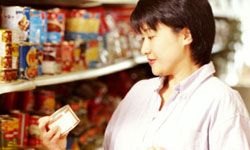 woman in grocery store looking at canned food