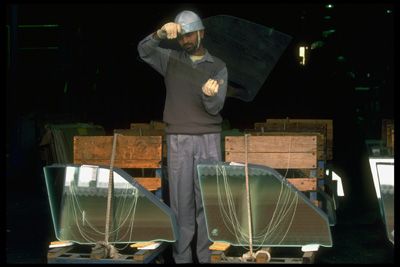 Workers checking safety glass for flaws.