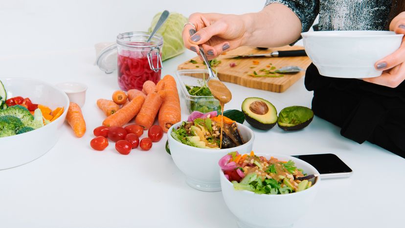 Woman pouring a salad dressing to a salad