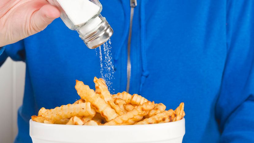 woman putting salt on frieds