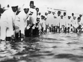 Young Nationalist supporters of Mahatma Gandhi break salt laws by filling containers with sea water in Bombay, India