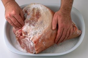 Man rubbing salt into cured ham