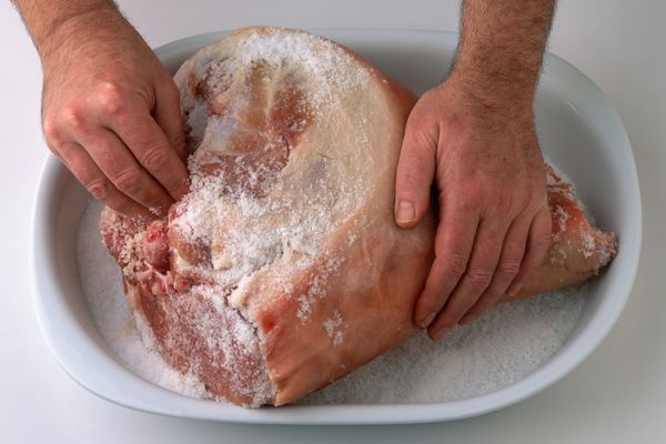 Man rubbing salt into cured ham