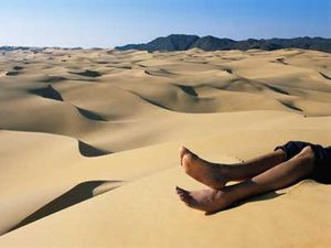 Solitary figure on arid sand dune.