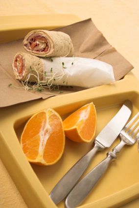 Lunch tray of a healthful wrap and orange slices.