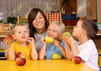 A teacher and three preschoolers taking a break from school for a fruit snack