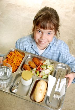 Schoolgirl carrying a tray with her school menu.