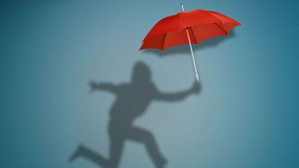 Shadow of businessman jumping and running with umbrella,