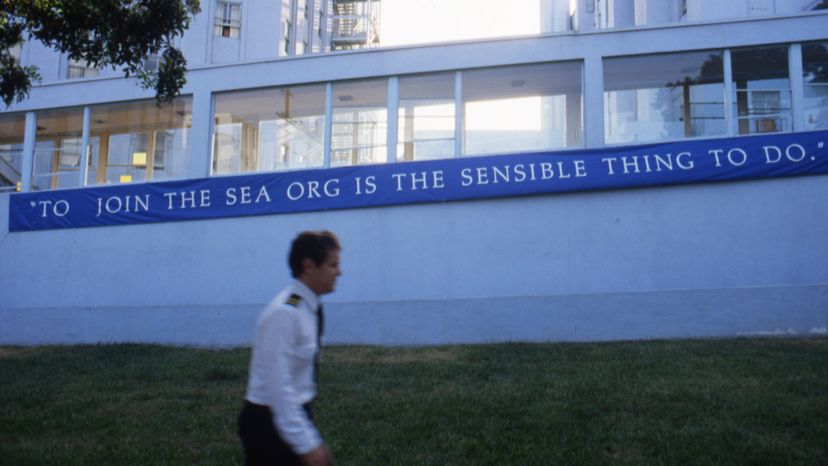A member of the 'Sea Org' walks by a sign outside the Church of Scientology Los Angeles on Sunset Boulevard. Michael Montfort/Michael Ochs Archives/Getty Images