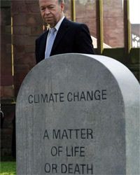 2009年3月19日，气候学家和美国宇航局科学家詹姆斯·汉森博士站在英国气候变化运动行动日的模拟墓碑旁。＂border=