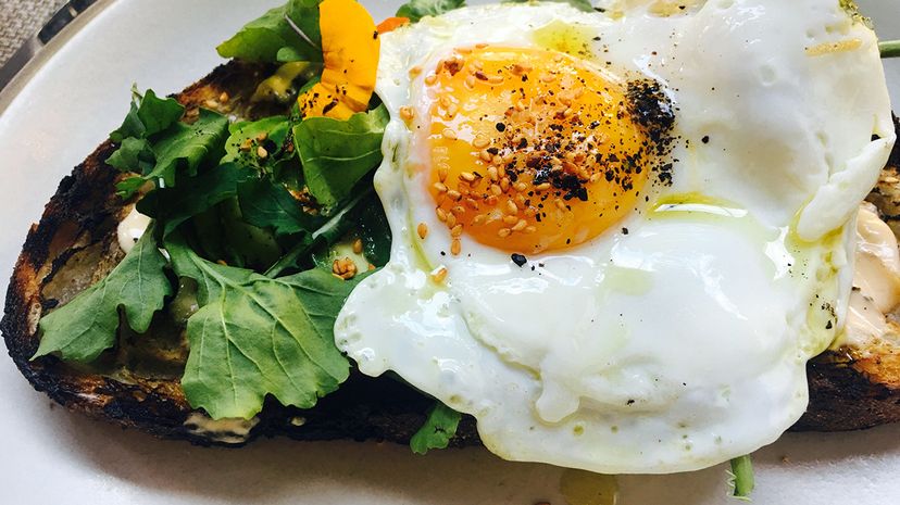 Starting the day off with a small healthy breakfast, like this high protein avocado toast topped with egg, can have many benefits. Westend61/Getty Images