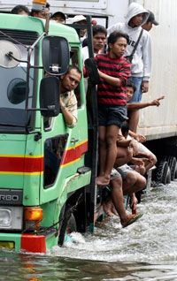 Jakarta, Indonesia residents ride a truck through flood waters.