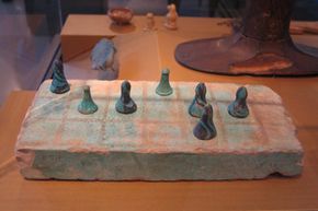 A weathered Senet board sitting in a museum display case.