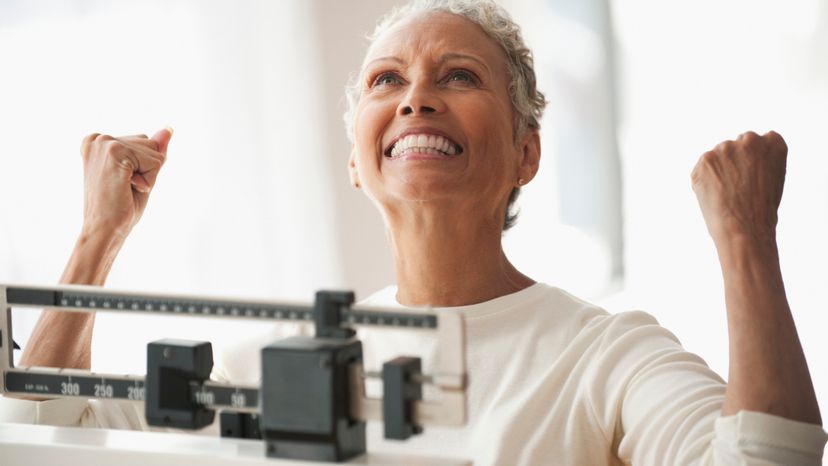 Woman celebrating senior weight loss on scale