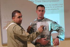 Senior medical officer and commander Maj. Adnan Najji explains the technique for applying a needle chest decompression using Spc. Christopher Graham, a brigade medic and health specialist. Senior medics are often in charge of teaching other medics.